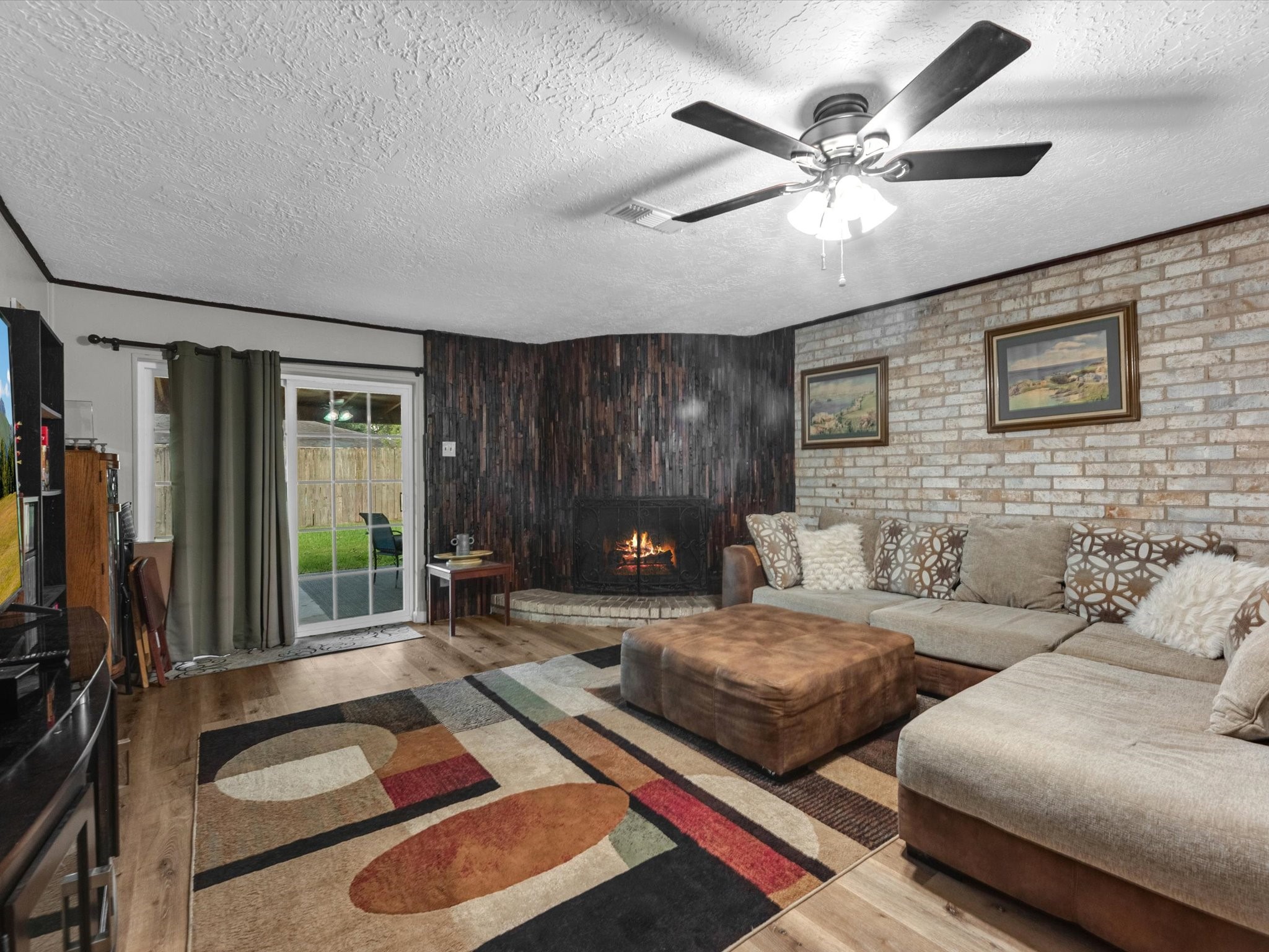 15714 Rill Lane Houston, TX 77062 - Photo 4 of 19 Your family room has ample space to entertain family and friends. This space features beautiful floors, neutral paint, brick accent wall, ceiling fan with lighting, and cozy fireplace.