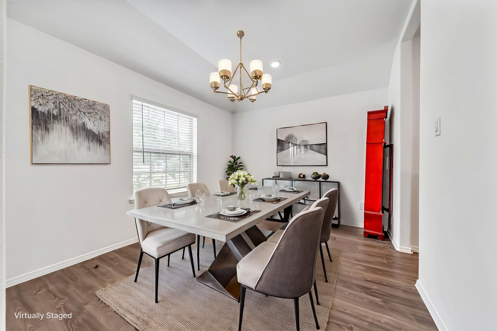 2847 Mistygate Court Conroe, TX 77301 - Photo 4 of 27 This photo showcases a bright, modern dining room with a sleek table set for six. The space features a stylish chandelier, large window providing natural light, and tasteful artwork on the walls. Wood flooring and neutral tones create a warm, inviting atmosphere.