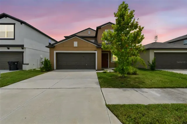 a front view of a house with a yard and a garage