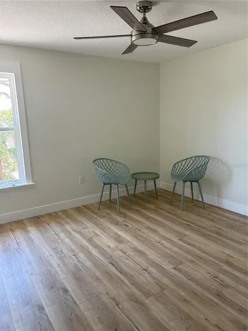 an empty room with wooden floor fan and windows