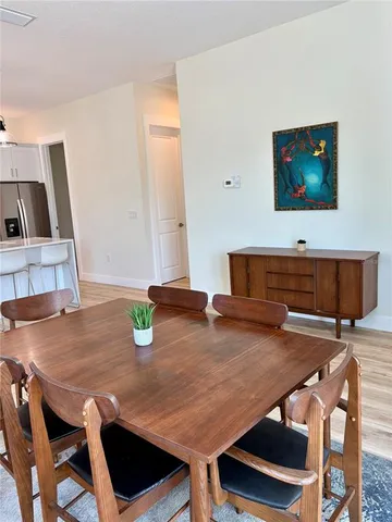 a open kitchen with stainless steel appliances granite countertop a sink dishwasher a stove top oven a dining table and chairs with wooden floor