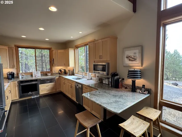 a kitchen with a stove a sink a counter top space and living room filled with furniture