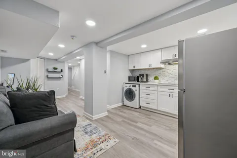 a living room with stainless steel appliances furniture a rug and a kitchen view