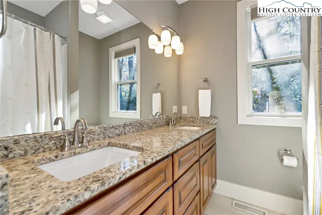 a bathroom with a granite countertop sink and a large mirror