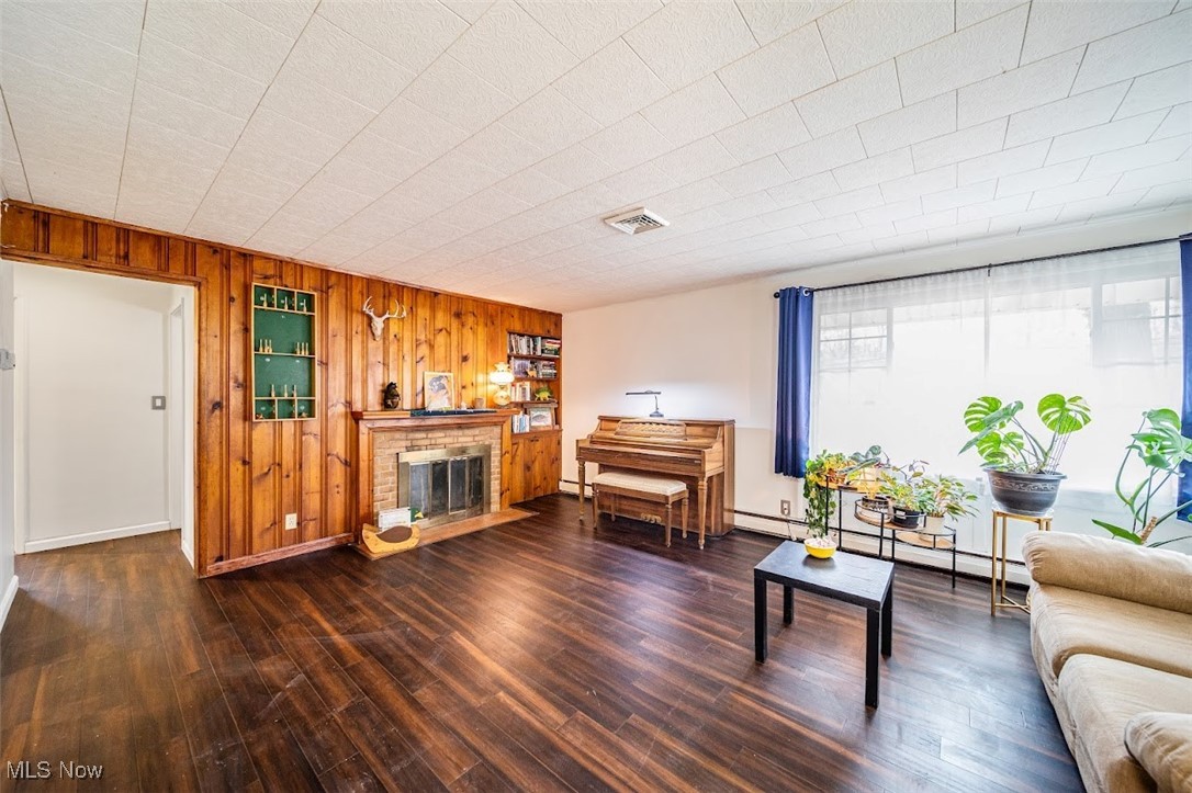 2510 Rockefeller Road Wickliffe, OH 44092 - Photo 13 of 33 Living room with wood walls, dark hardwood / wood-style floors, and a brick fireplace