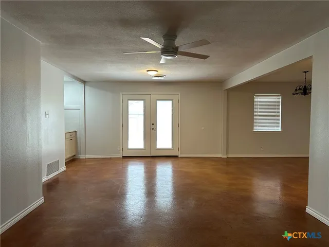 a view of an empty room with window and wooden floor