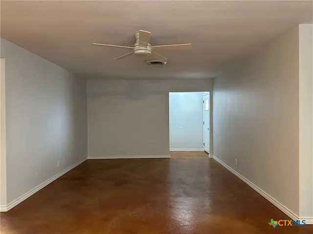 an empty room with wooden floor and fan