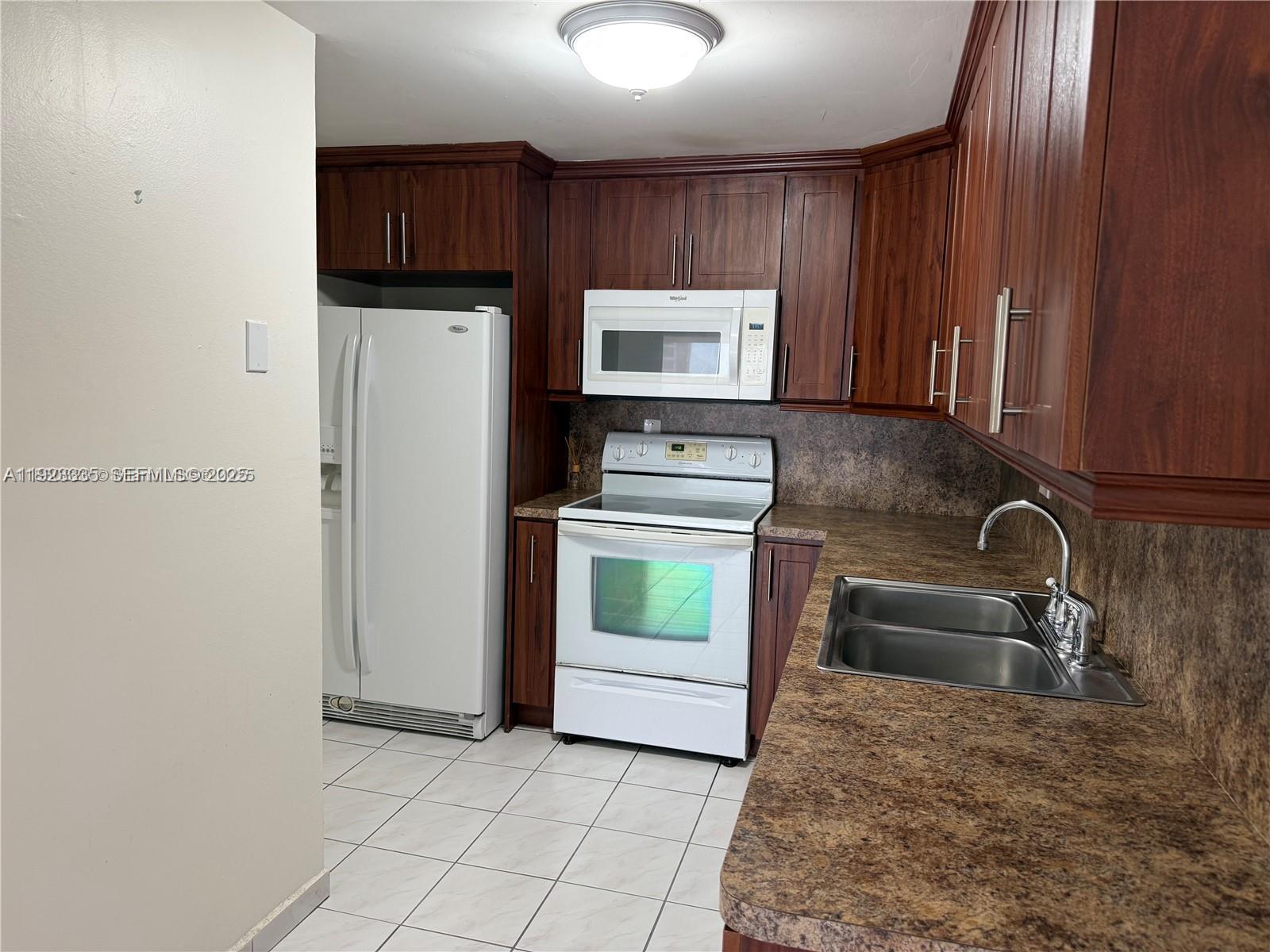 14250 Southwest 62nd Street, Unit 524 Miami, FL 33183 - Photo 5 of 27 a kitchen with a refrigerator sink and cabinets