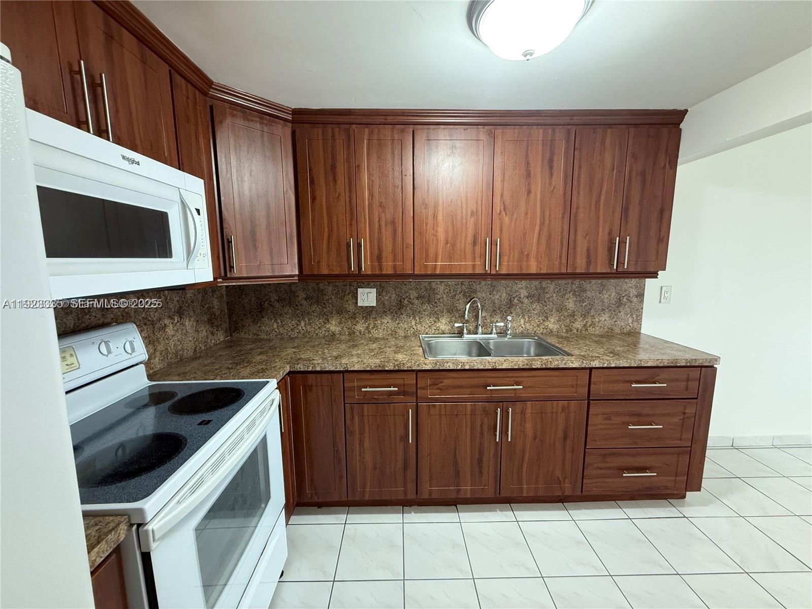 14250 Southwest 62nd Street, Unit 524 Miami, FL 33183 - Photo 6 of 27 a kitchen with granite countertop a stove microwave and cabinets