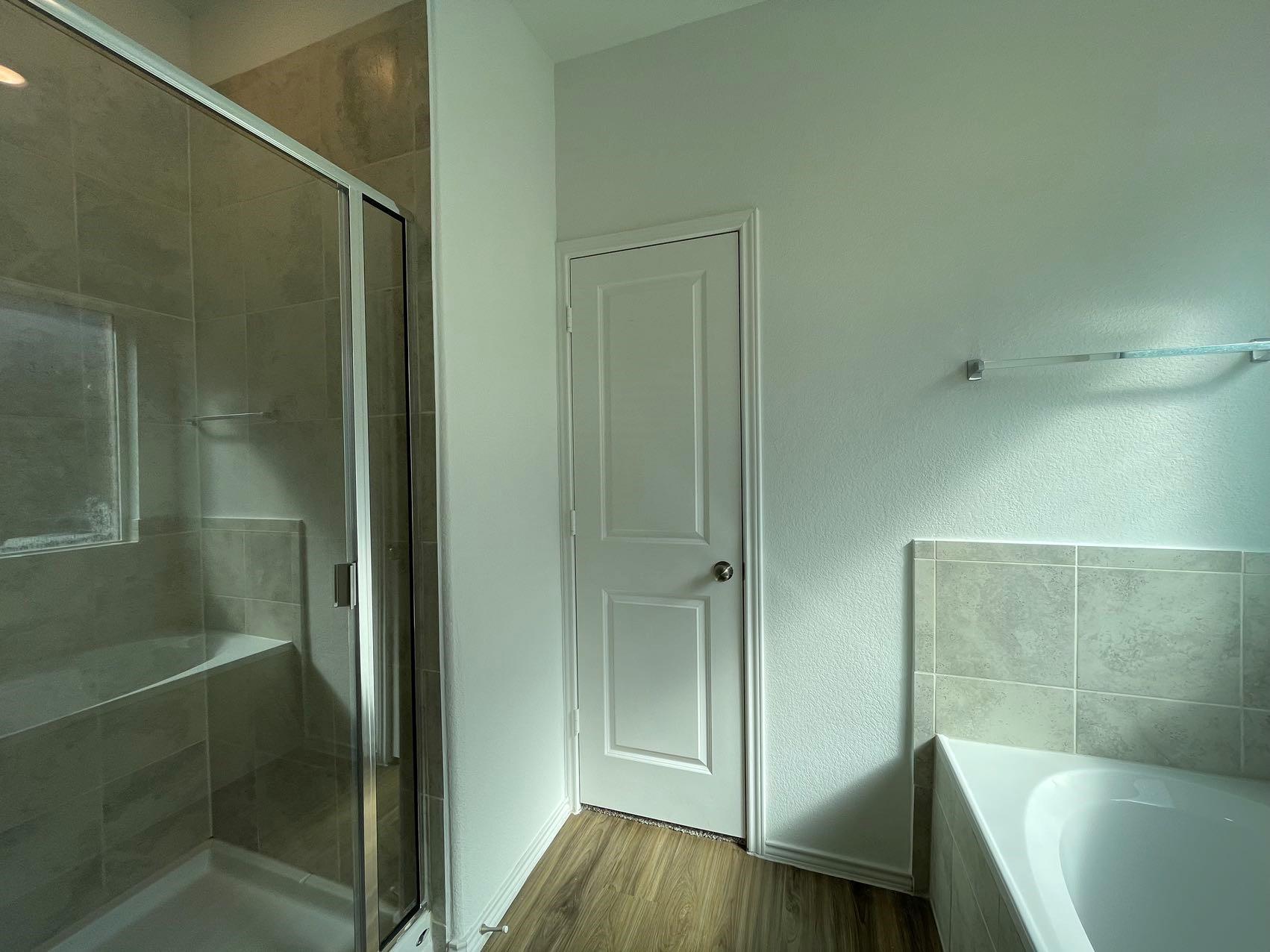 1625 Woolsey Way Leander, TX 78641 - Photo 13 of 17 This bathroom features a spacious shower with glass enclosure and tiled walls, a built-in shower bench, and a separate bathtub with tiled surround