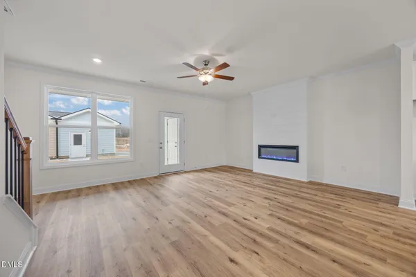 an empty room with wooden floor chandelier fan and windows