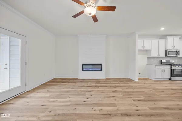 a view of empty room with wooden floor and fan
