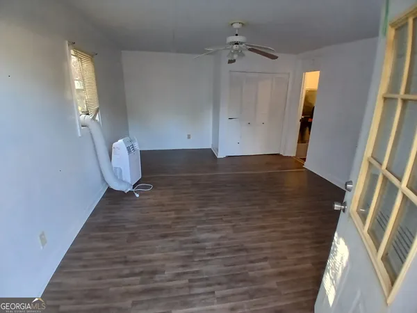 a view of an empty room with wooden floor and a window