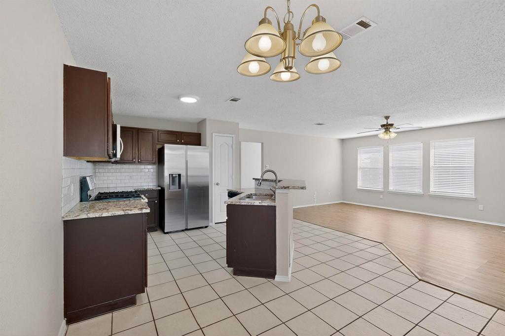 1207 Aberdeen Drive Allen, TX 75002 - Photo 11 of 40 a kitchen with stainless steel appliances granite countertop a stove top oven a sink dishwasher and white cabinets with wooden floor