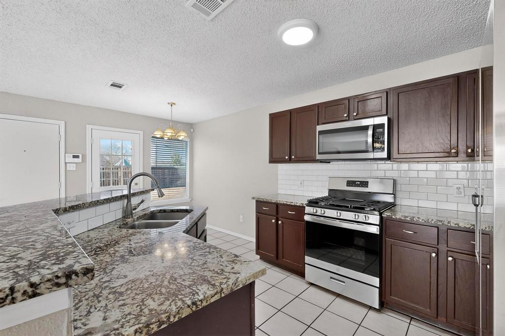 1207 Aberdeen Drive Allen, TX 75002 - Photo 14 of 40 a kitchen with stainless steel appliances granite countertop a stove microwave and sink
