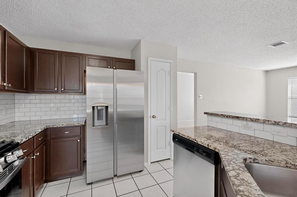 1207 Aberdeen Drive Allen, TX 75002 - Photo 15 of 40 a kitchen with granite countertop a refrigerator stove and cabinets