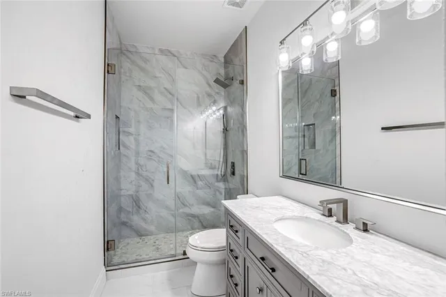 a bathroom with a granite countertop shower a sink and a toilet