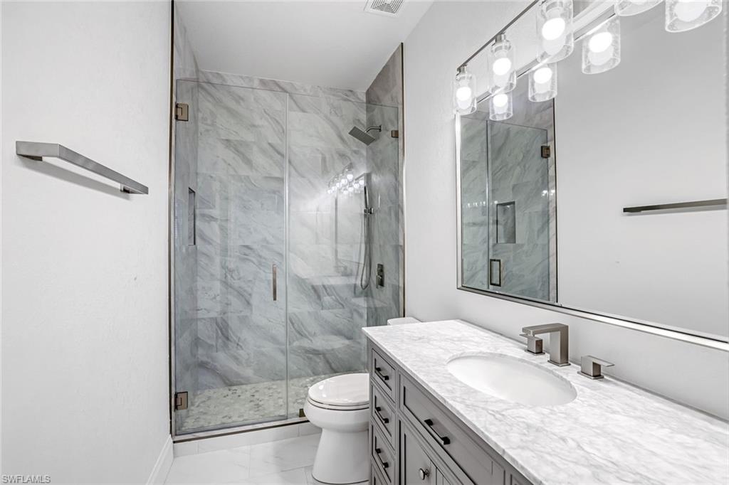 630 Lalique Circle, Unit 506 Naples, FL 34119 - Photo 17 of 25 a bathroom with a granite countertop shower a sink and a toilet