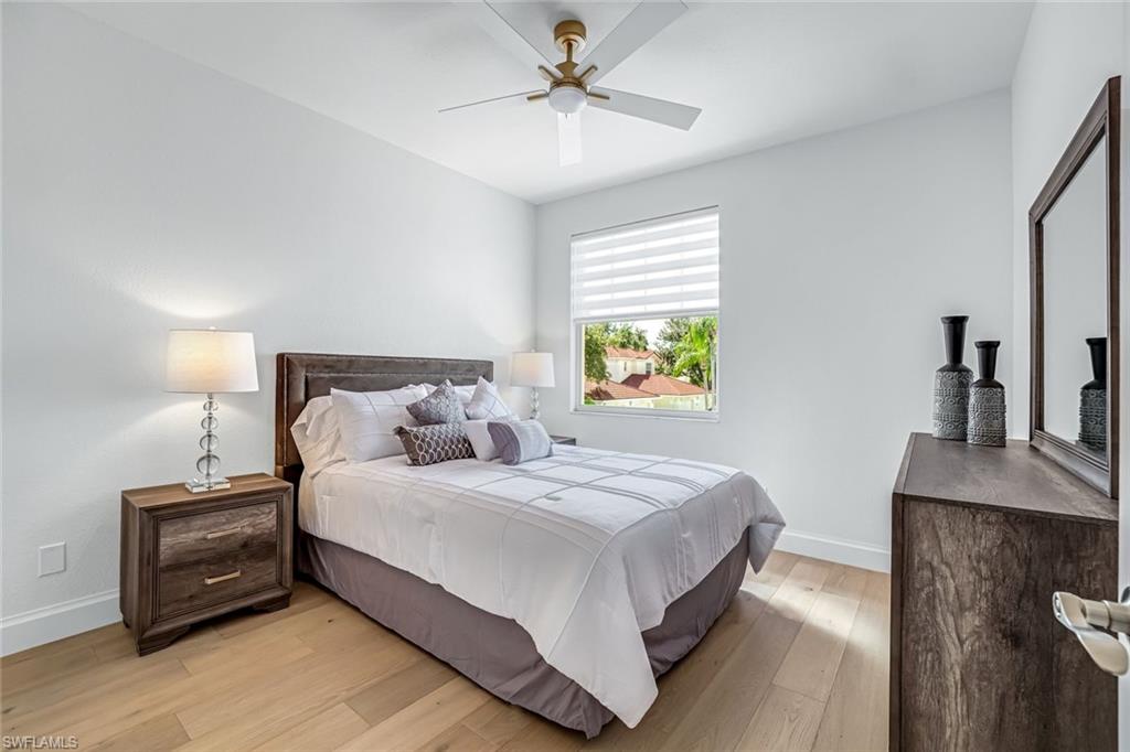 630 Lalique Circle, Unit 506 Naples, FL 34119 - Photo 19 of 25 a bedroom with a bed and a chandelier