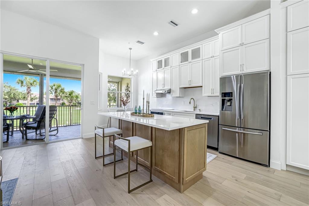 630 Lalique Circle, Unit 506 Naples, FL 34119 - Photo 6 of 25 a kitchen with stainless steel appliances granite countertop a table chairs refrigerator and a sink