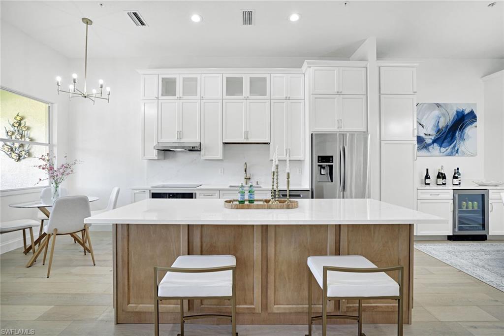 630 Lalique Circle, Unit 506 Naples, FL 34119 - Photo 9 of 25 a kitchen with stainless steel appliances granite countertop a table chairs sink refrigerator and cabinets