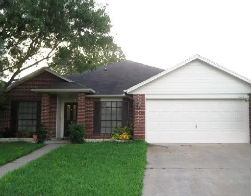 a view of a house with a small yard and a large tree