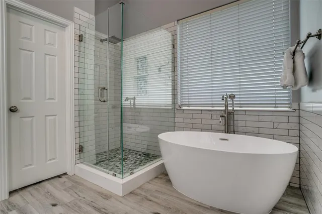 a white bath tub sitting in a bathroom next to a shower