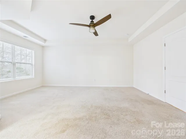 an empty room with windows and ceiling fan