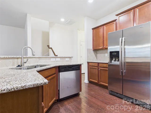 a kitchen with stainless steel appliances granite countertop a sink and a refrigerator