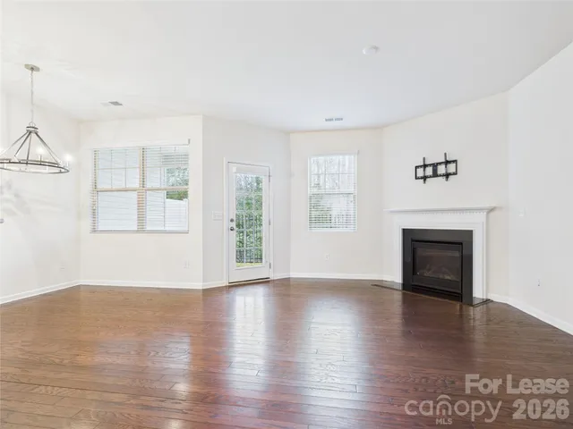 an empty room with wooden floor fireplace and windows