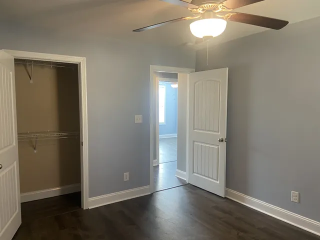 an empty room with wooden floor closet and windows