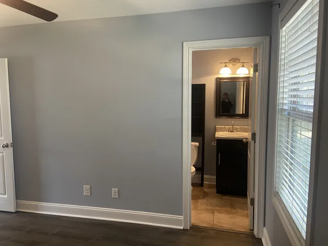 a view of a hallway with wooden floor and a bathroom