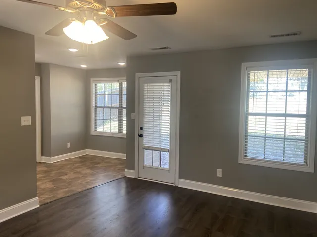 an empty room with wooden floor and windows