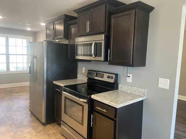 a kitchen with stainless steel appliances granite countertop a refrigerator a stove a sink and a microwave