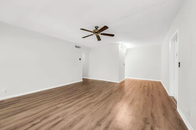 an empty room with wooden floor and fan