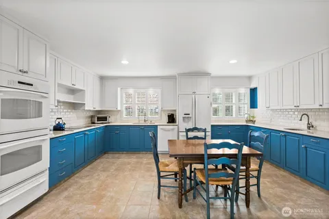 a kitchen with granite countertop a table chairs microwave and cabinets