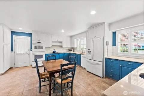 a kitchen with stainless steel appliances granite countertop a table chairs sink refrigerator and cabinets