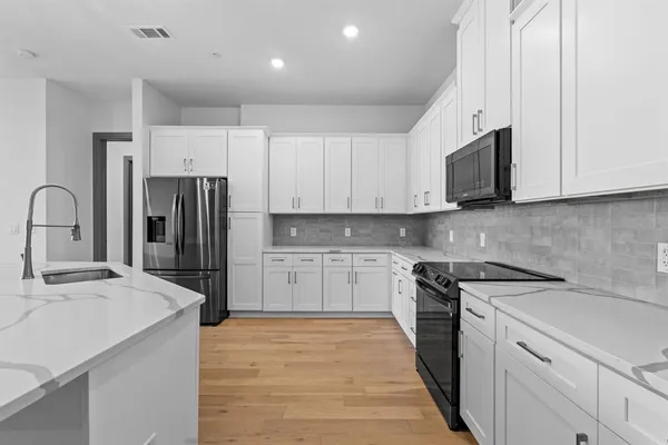 a kitchen with granite countertop white cabinets and black appliances