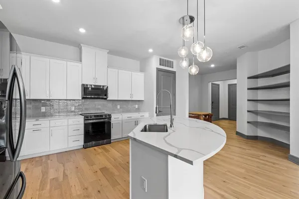 a large kitchen with stainless steel appliances kitchen island granite countertop a refrigerator a stove a sink and a wooden floors