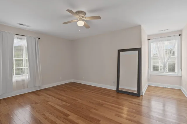 an empty room with wooden floor and windows