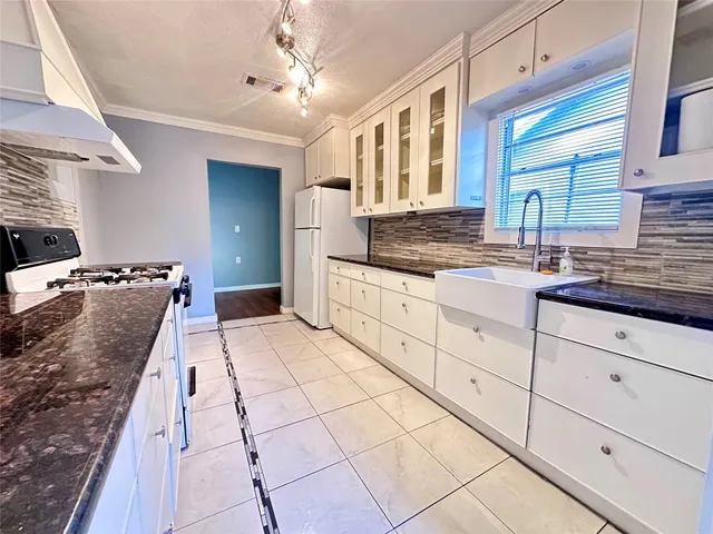 a large white kitchen with a stove a sink dishwasher and cabinets