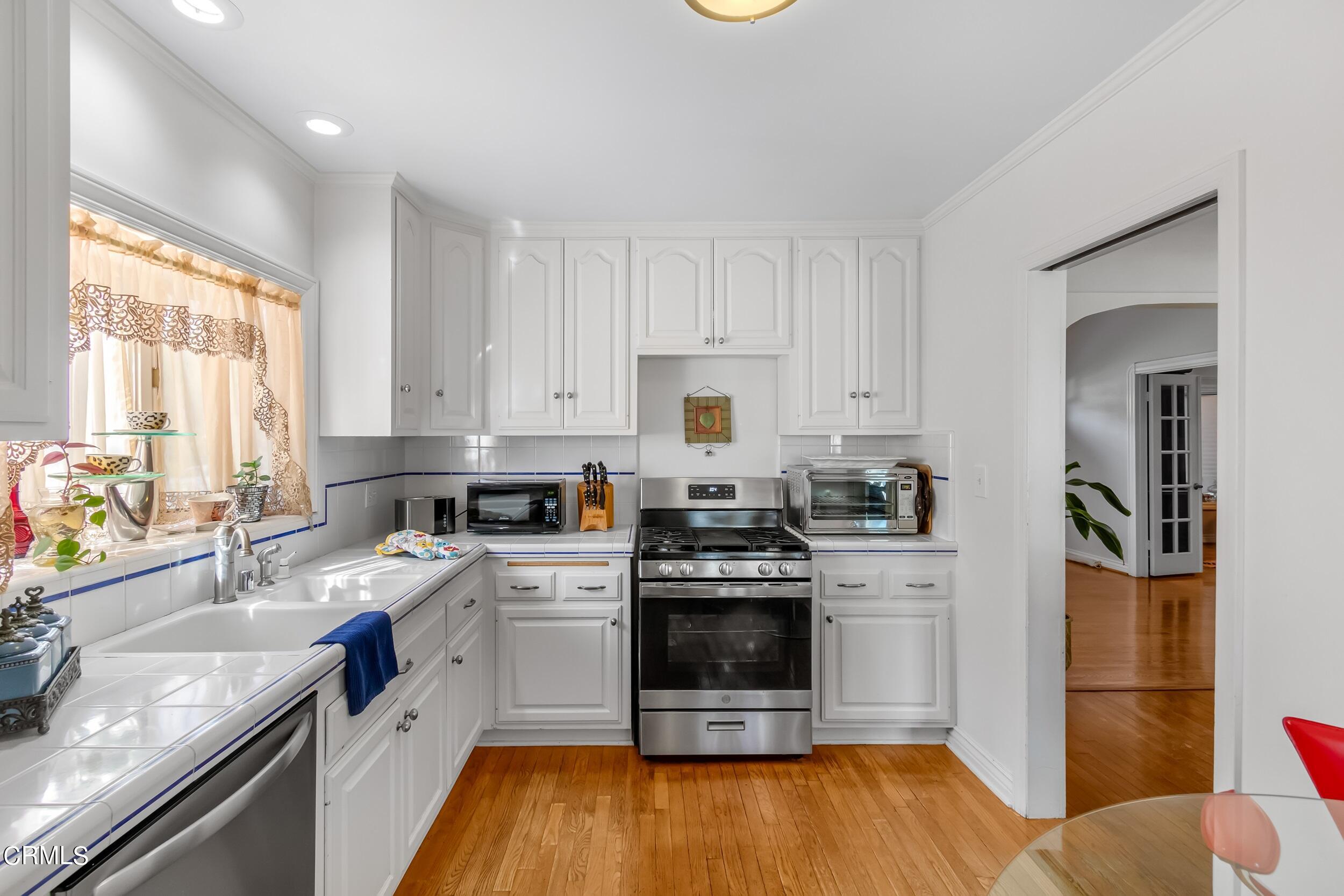432 West Poppyfields Drive Altadena, CA 91001 - Photo 7 of 23 a kitchen with a sink white cabinets and stainless steel appliances
