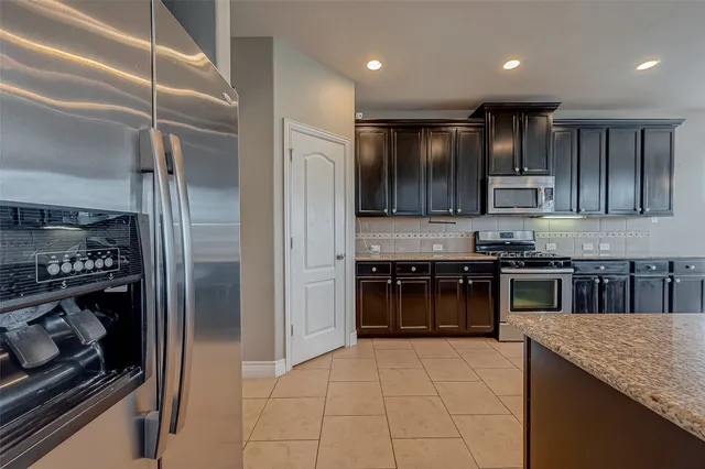 a kitchen with kitchen island granite countertop a stove and a refrigerator