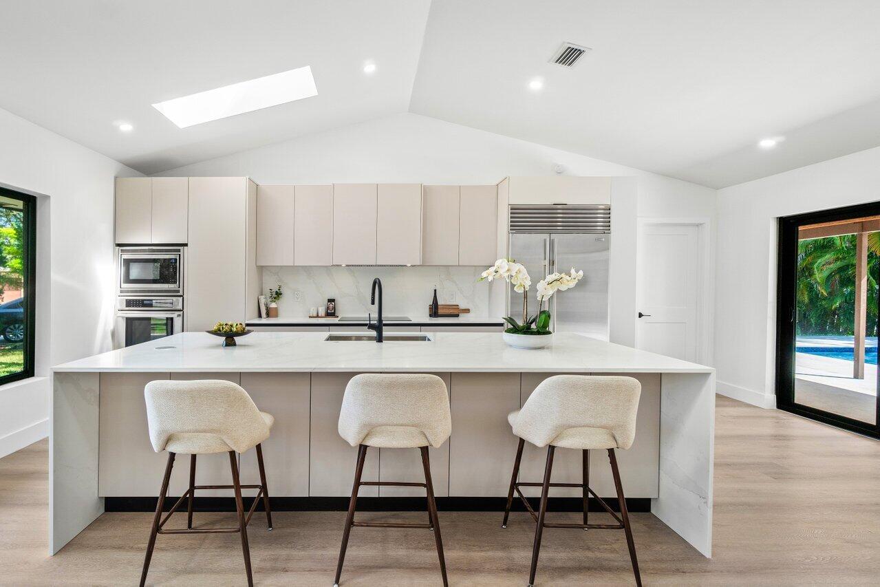 4408 Nicole Circle Tequesta, FL 33469 - Photo 10 of 29 a white kitchen with a sink and chairs