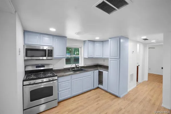 a kitchen with stainless steel appliances a stove a sink a microwave a refrigerator and cabinets