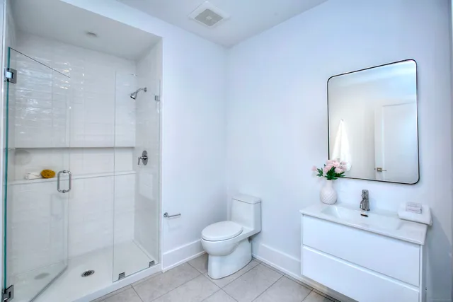 a bathroom with a toilet a sink a mirror and shower