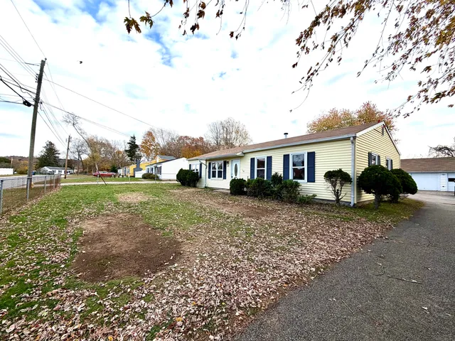 a view of a white house next to a yard with big trees
