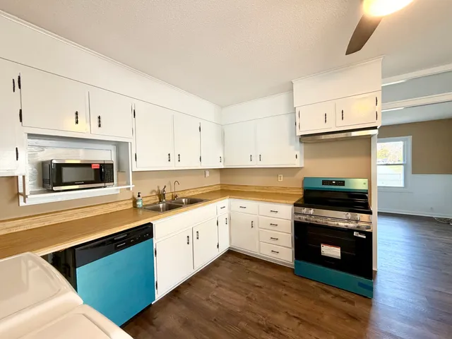 a kitchen with granite countertop a stove top oven a sink dishwasher and a refrigerator with wooden floor