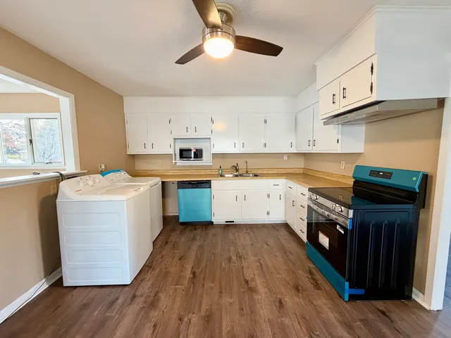 a kitchen with wooden floors and white stainless steel appliances