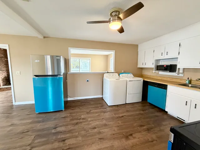 a kitchen with stainless steel appliances granite countertop a refrigerator a sink dishwasher and white cabinets with wooden floor